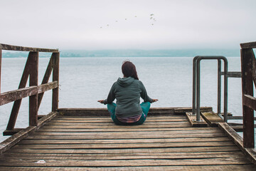 Fototapeta premium young woman meditating in front of the sea