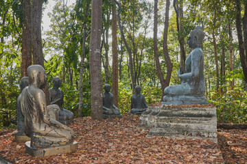 Phayao, Thailand - Dec 6, 2020: Left View of Buddha Statue Giving The First Sermon with 5 Disciples on Forest Backgroud in Wat Analayo Temple