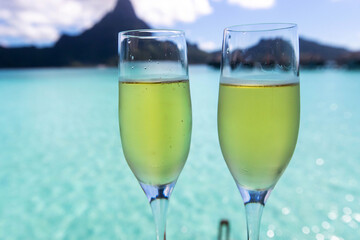 Two champagne glasses at romantic vacation destination Bora Bora in front of ocean lagoon with Mt. Otemanu in the background