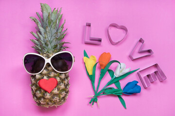 Pineapple with sunglasses, message love, tulip flowers on pink background. Happy women's day concept