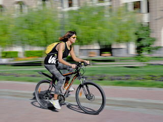Naklejka na ściany i meble Side View Of Young Woman Riding Bicycle On Road