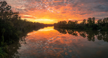 Fototapeta na wymiar Spectacular Riverside Sunrise with Cloud Reflections