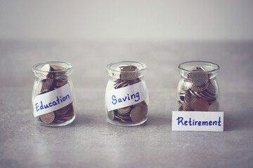 Coins in glass money jar with Education, Saving and Retirement fund label, financial concept. 
