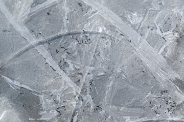 Frozen water in the aggregate state of ice. Cracks and air bubbles in the ice. Cold season, winter concept.
