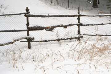Rural winter scene. Snow covered wooden fence brown logs panoramic background