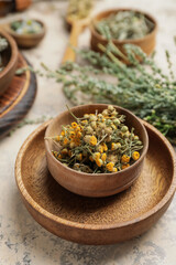 Wooden bowl with dried herbs on table