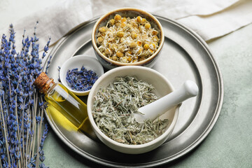 Composition with different herbs and bottle of essential oil on table