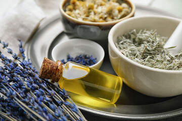Composition with different herbs and bottle of essential oil on table, closeup
