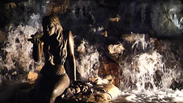 mermaid statue structure with water around in a public park 