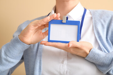 Young woman with blank badge on color background, closeup