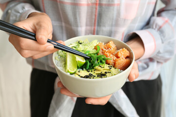 Woman with tasty rice poke bowl