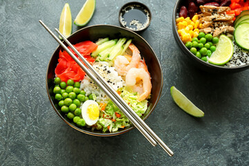 Bowls with tasty rice, shrimps and vegetables on dark background