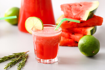 Glass of fresh watermelon juice and lime on light background