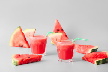 Glasses of fresh watermelon juice on light background