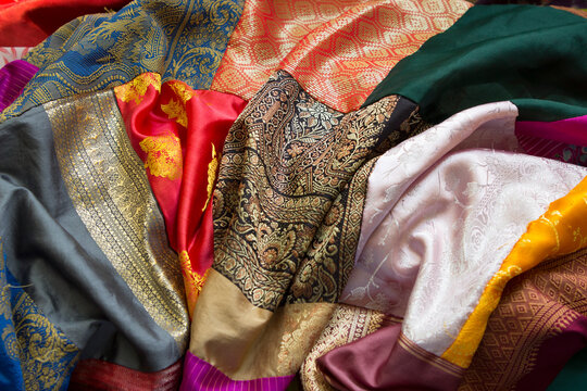 Many colorful bright vintage retro silk shawls, fabric with patterns and designs at a flea market or in an antique store.