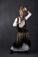 Beautiful girl in steampunk style costume with hat and handgun