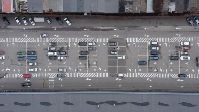car parking lot free of charge aerial view. Overhead aerial of a car trying to find a parking spot in a busy parking lot. Aerial top view of many cars parked.