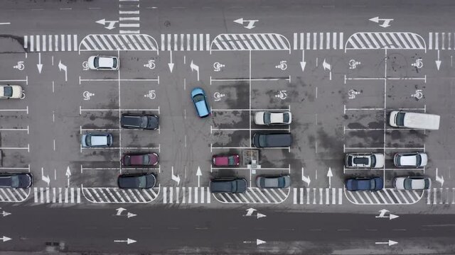 car parking lot free of charge aerial view. Overhead aerial of a car trying to find a parking spot in a busy parking lot. Aerial top view of many cars parked.