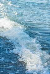 Vertical photograph of a sea wave partially illuminated by the sun at sunrise