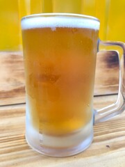 Lager Draught in Glass Mug on Wood Bar with Yellow Background