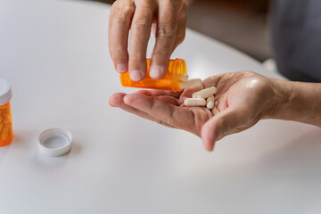 Senior man holding pills on hand. Medicine and health care concept.
