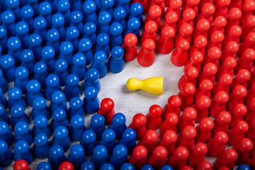 blue and red wooden figurines surrounding a fallen yellow figurine, symbol for failed leader