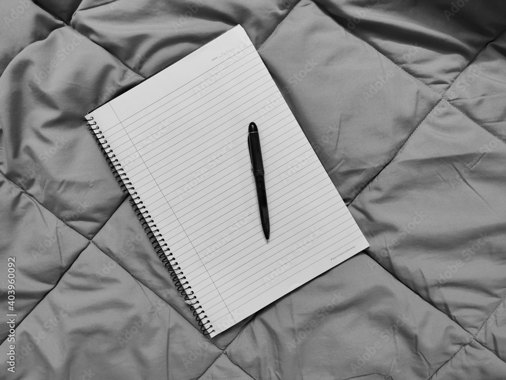 Poster grayscale top view of a notebook and pen on a bedding