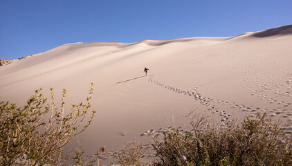 hombre subiendo una monta&ntilde;a de arena en el desierto c&aacute;lido