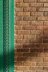 Close up full frame abstract background of a vintage textured brown brick wall, surrounded with intricate green painted wood moulding 