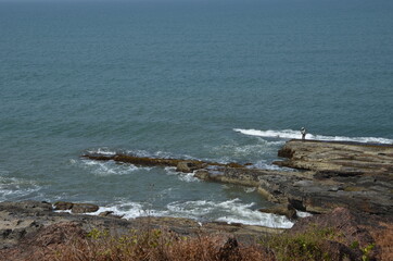 Fisherman on the rocky coast of the Arabian Sea. North Goa, India