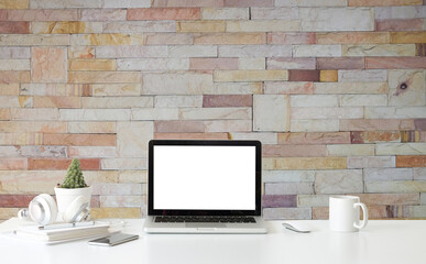 Mock up laptop on stylish workspace with brick wall. Blank screen monitor for graphic display montage.