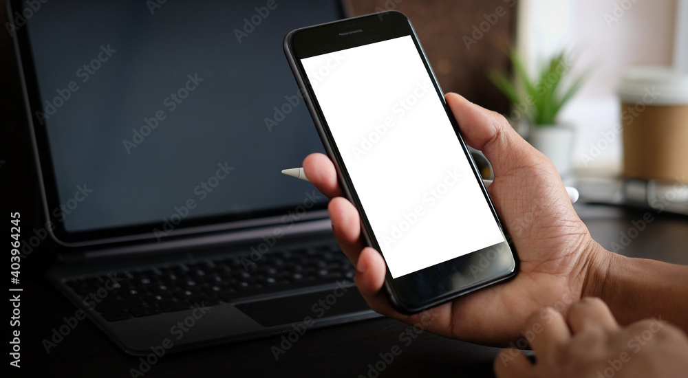 Poster close up view of man hand holding mock up smart with blank screen at his modern workspace.blank scre