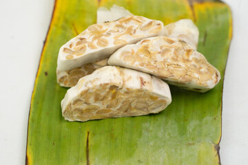tempe or tempeh wrapped in banana leaves,is a indonesian traditional food.made of fermented soya beans.isolated white background