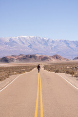 Hombre caminando por la carretera hacia una enorme montaña nevada