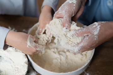 Mother and daughter with flour together in the kitchen prepare dough in a bowl.