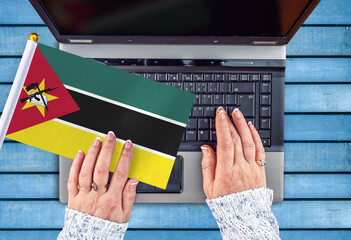 woman hands and flag of Mozambique on computer, laptop keyboard 