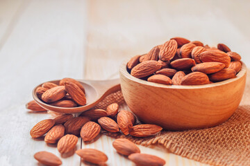 Almonds in a wooden bowl The nuts are freely placed on the dark board.
