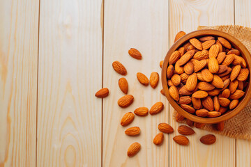 Top view of almonds on a wooden table Almonds in a wooden bowl The nuts are freely placed on the dark board.
