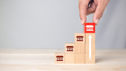 Franchise business,Businessman hand choose wooden blog with franchise marketing icons Store....