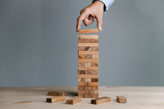 Planning,risk and strategy in business, businessman placing wooden block on a tower.