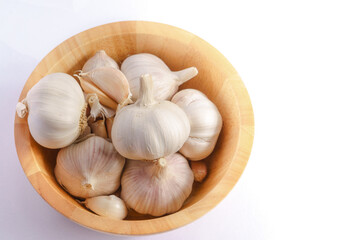 Garlic in a wooden bowl on a white background