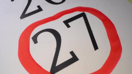 27 - Marking the date in the calendar with a red marker. The twenty-seventh day of the month. The hand circles the date in the calendar with a pen. Number in the red circle close up