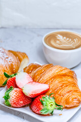 Continental breakfast with croissants. Coffee and fresh strawberries