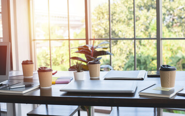 coffee in paper cup ,Laptop and notebook on wooden table in office