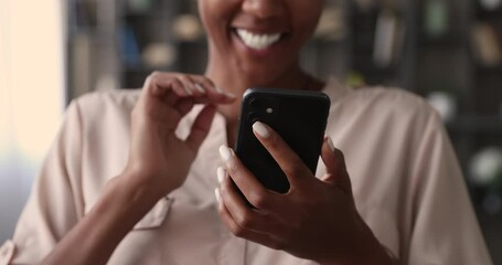 Happy smiling african woman hold mobile phone, close up on female hands and device. Customer buying goods via internet, play new exciting game, chatting online share videos photos with friend concept - Powered by Adobe