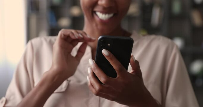 Happy smiling african woman hold mobile phone, close up on female hands and device. Customer buying goods via internet, play new exciting game, chatting online share videos photos with friend concept