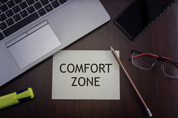 Comfort zone card. Top view of office table desktop background with laptop, phone, glasses and pencil with card with inscription comfort zone. Business concept.