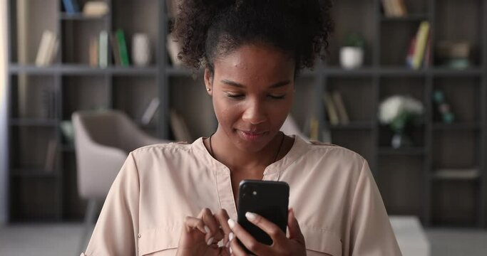 Mixed race young attractive woman holding modern smartphone enjoy remote chat with friend. Learn new cool freeware application, share photos and videos in social media network, share messages concept
