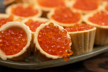Naklejka na ściany i meble Tartlets with salmon caviar on a platter. Close-up, selective focus.