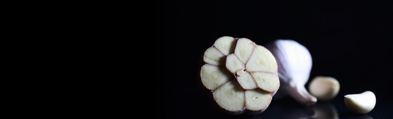 Fresh garlic clove on black background. Garlic is rich in vitamins, useful spring, good spices. Garlic sliced on a dark background. Raw sliced garlic.